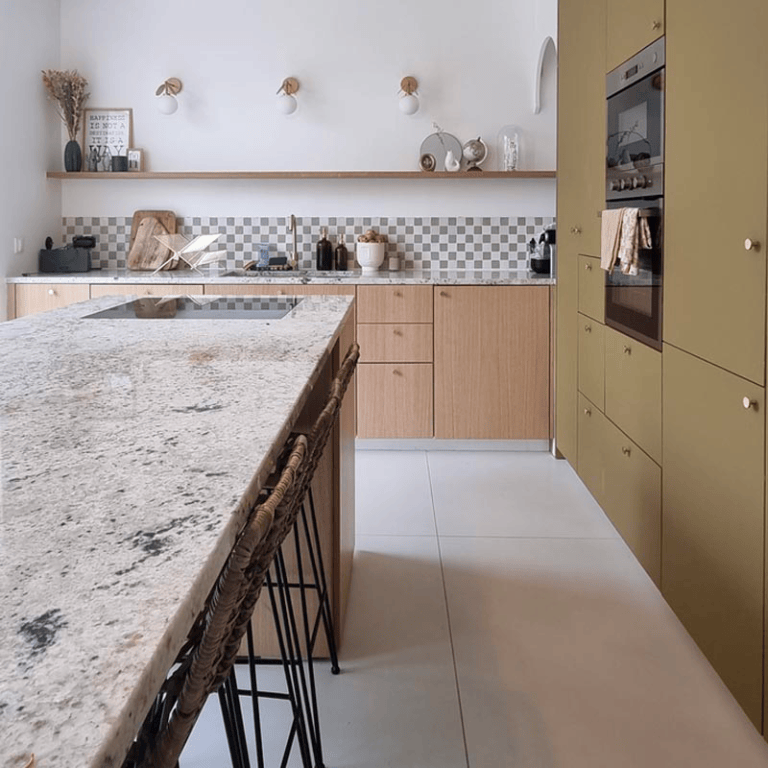 Une cuisine avec un grand îlot central en pierre, des façades en bois clair et des détails de décoration soignés.