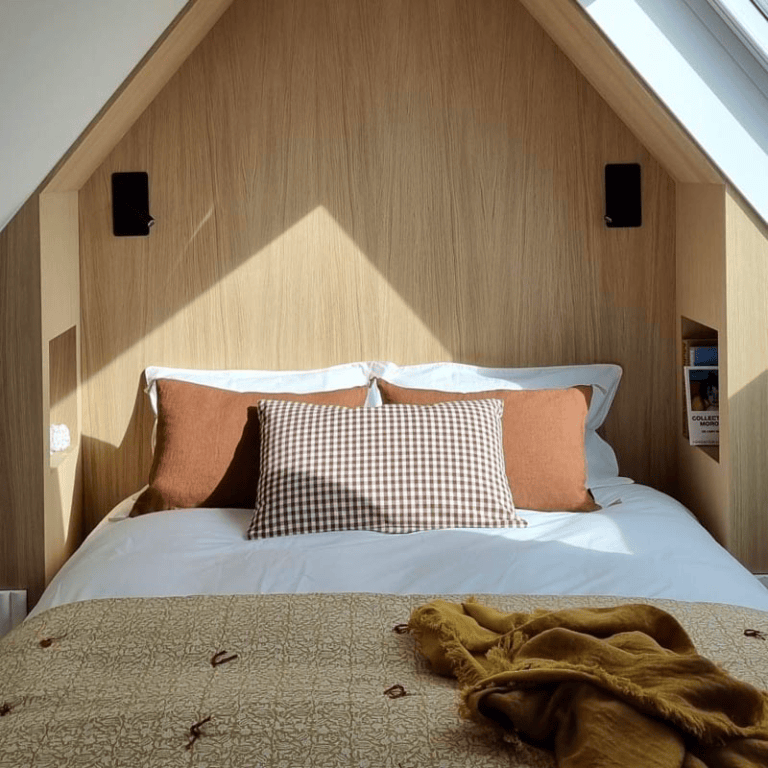Aménagement d'un lit dans des combles, fait sur-mesure avec des tables de chevets intégrées.