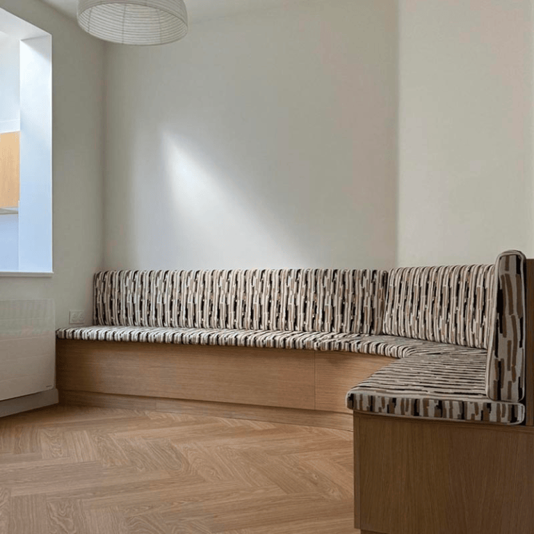 Une banquette d'angle sur-mesure faites de bois et de tissus.