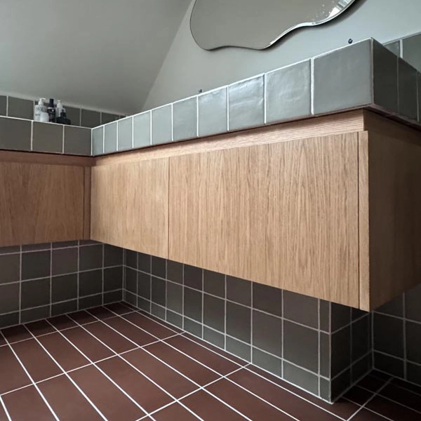salle de bain de carrelages verts et rouges avec meubles en bois et miroir abstrait